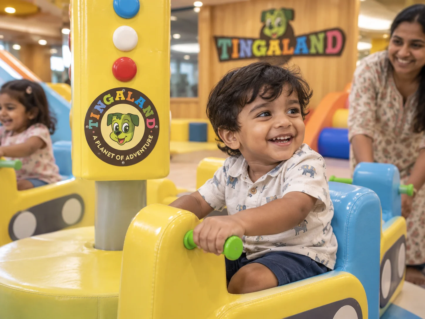 Toddler holding the merry go round handle beside tingaland branding