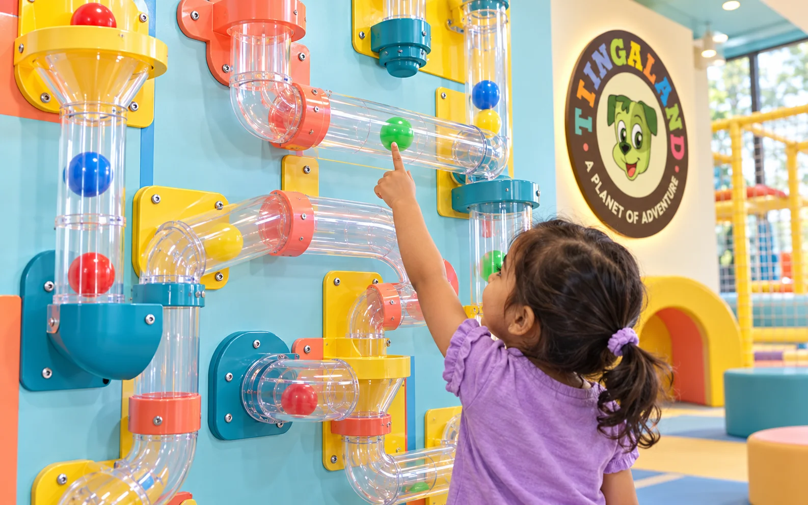 Toddler points to a green ball inside the transparent maze