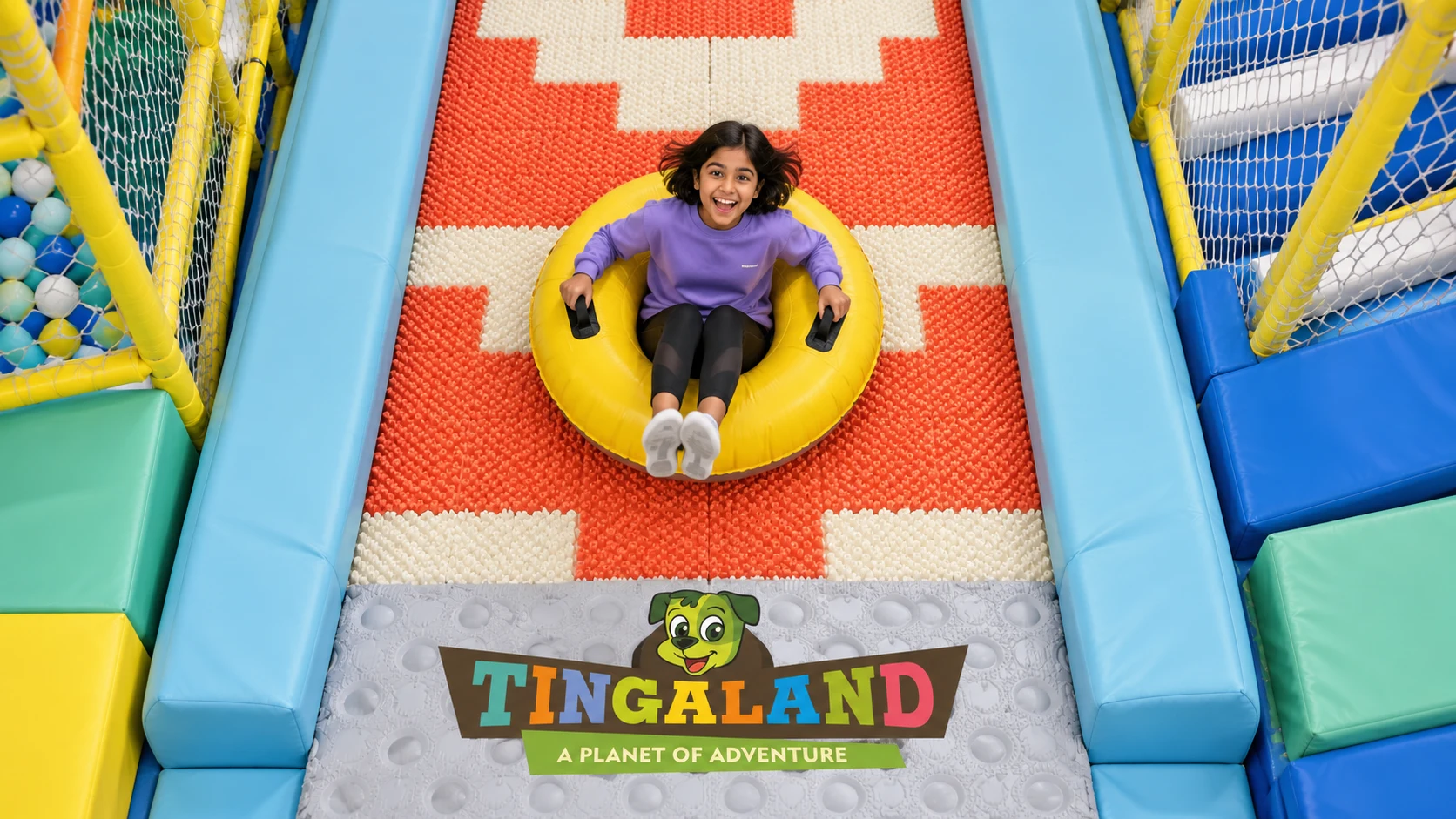 Overhead view of a girl riding a yellow donut ring down the patterned slide