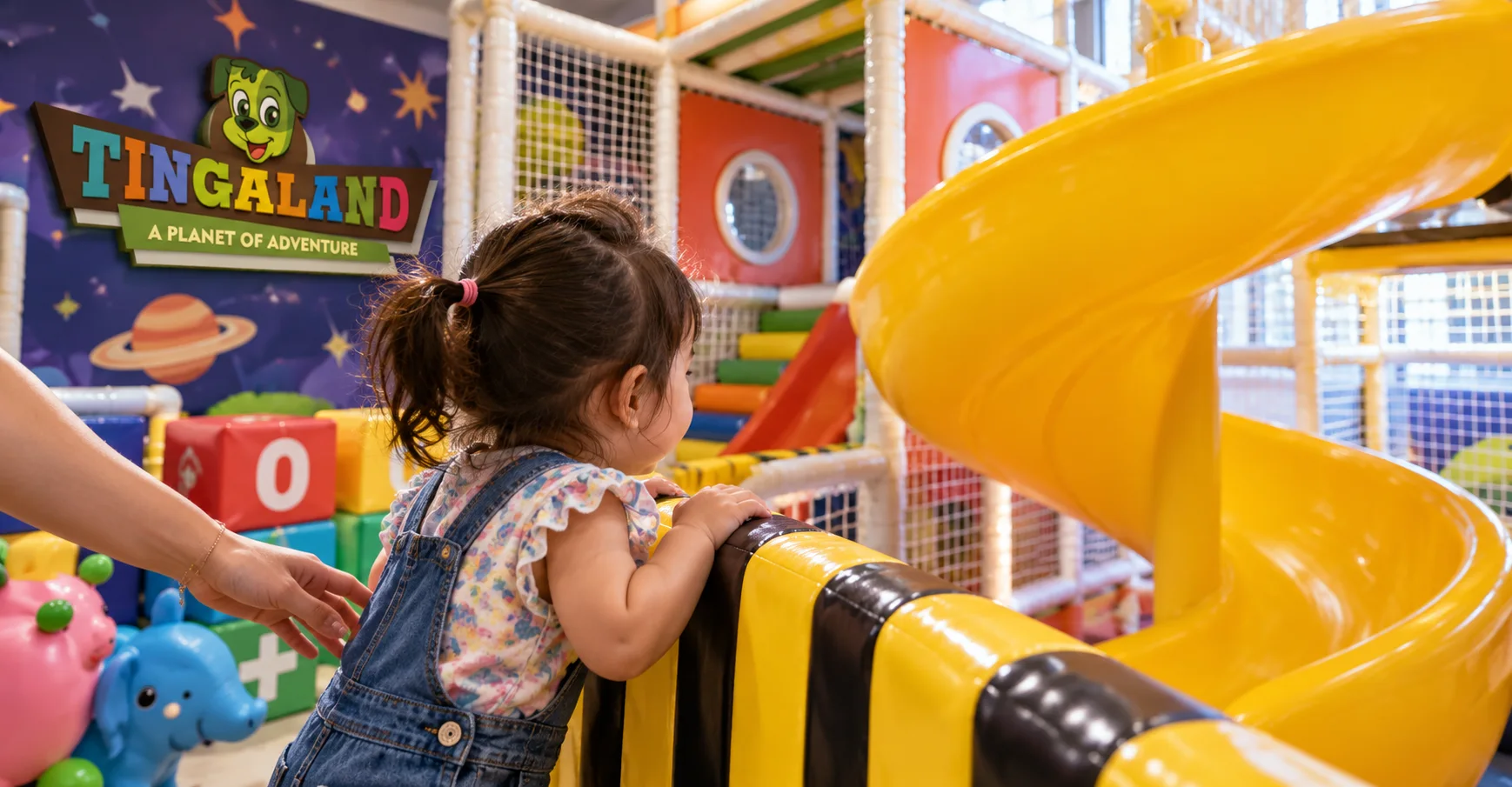 Toddler spiral slide 7 Toddler looks at the curved yellow slide beside a padded rail